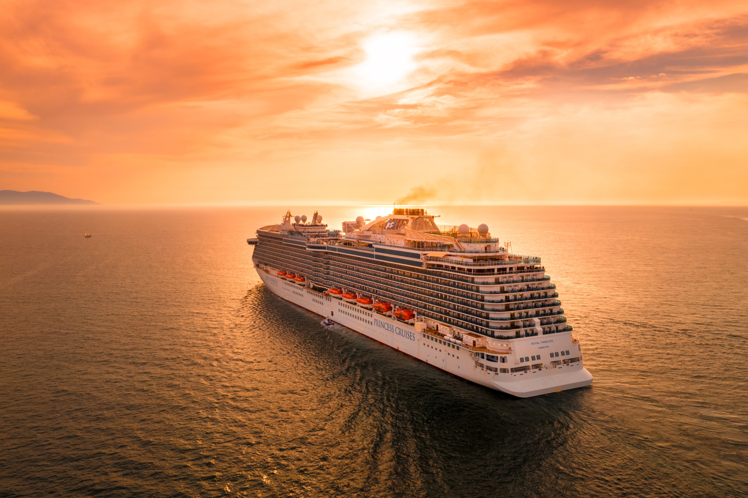 cruise ship in water with orange sunset