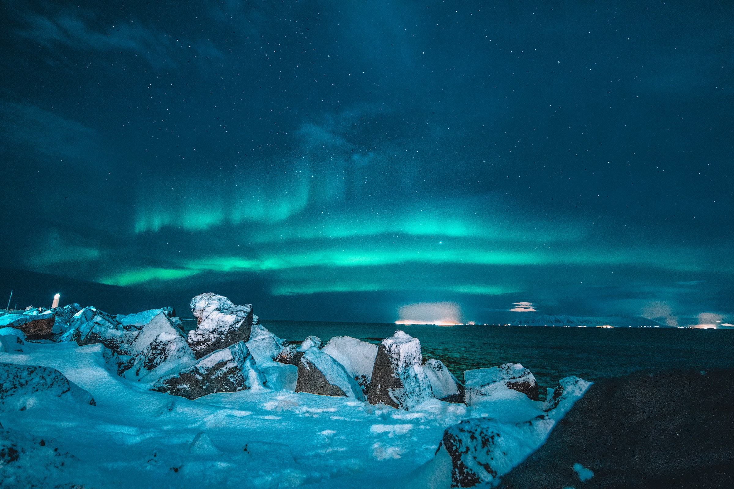 snowy rocks with aurora borealis in night sky