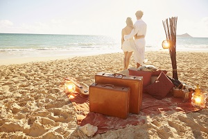Caucasian couple with suitcases on tropical beach